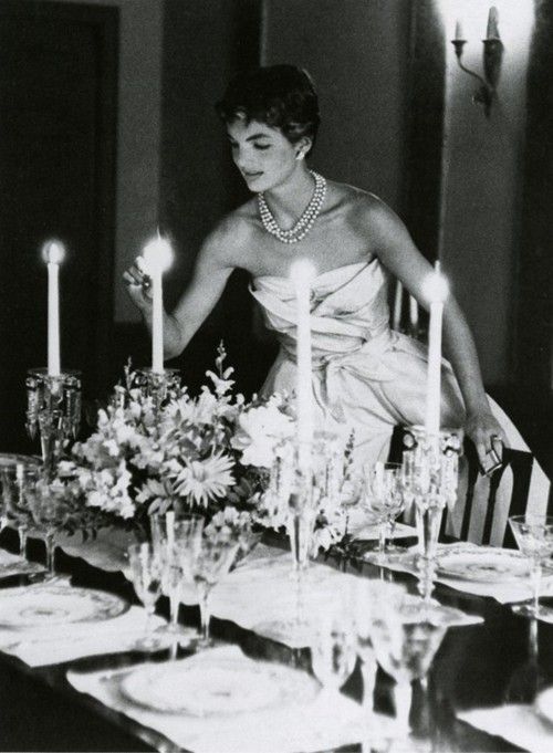 Jackie Kennedy lighting candles in a very glam gown